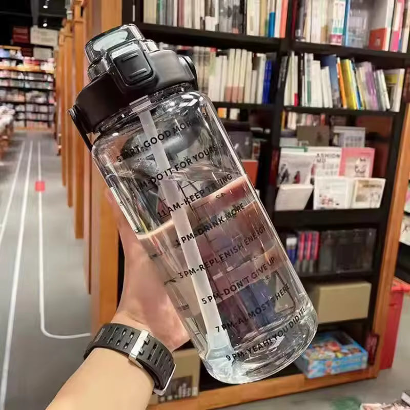 Clear 2 liter water bottle for girls with time marker for hydration tracking held in hand