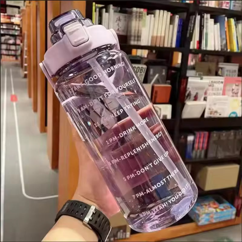 Clear 2 liter water bottle for girls with motivational time markers and pink lid held in hand