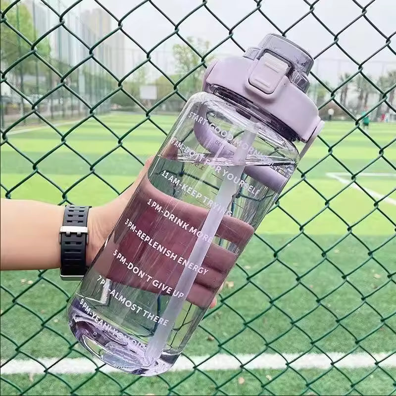 Transparent 2 liter water bottle for girls with purple lid and motivational time markers held outdoors