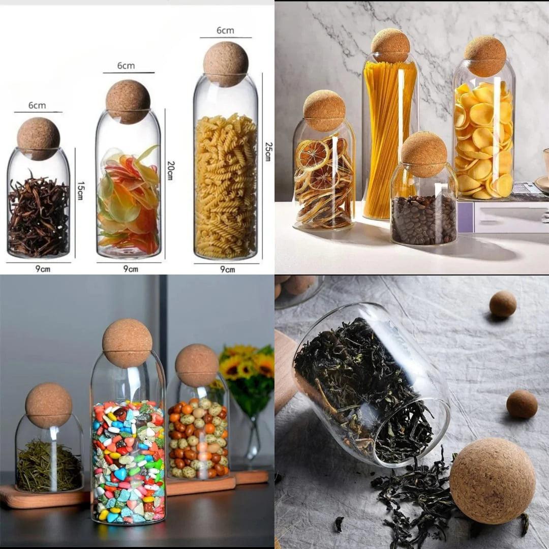 Set of glass storage jars with cork lids in various sizes holding pasta, dried fruits, coffee beans, and herbs
