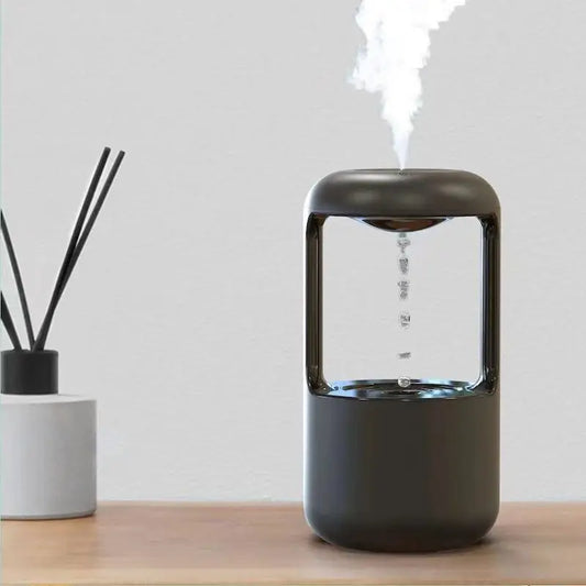 Clarify.pk glow in the dark air humidifier releasing mist on a wooden surface with decorative diffuser sticks