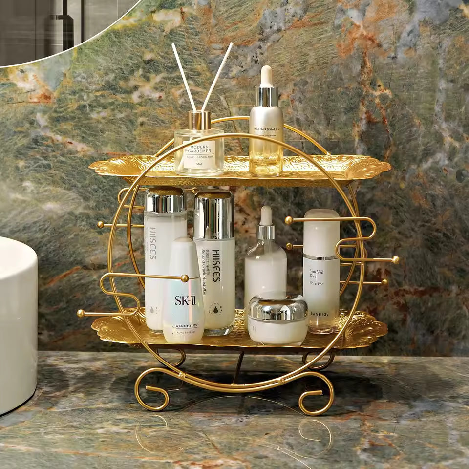 Clarify.pk gold metal 2 tier bathroom organizer holding skincare bottles on marble countertop