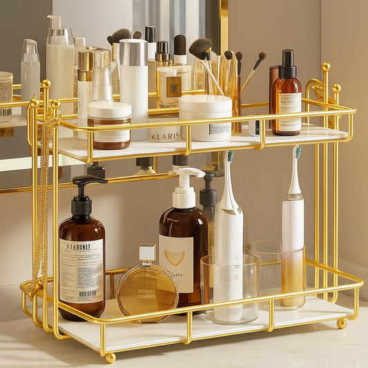 Gold bathroom vanity organizer with two tiers holding skincare bottles, makeup brushes, and electric toothbrushes