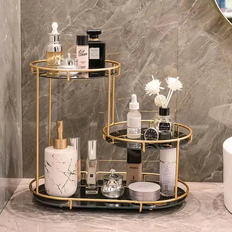 Clarify.pk two-tier gold cosmetics organizer with various skincare and fragrance bottles on marble bathroom counter