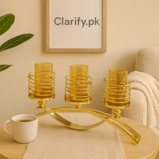 Elegant golden triple candle holder with spiral design and three glass cups on wooden table