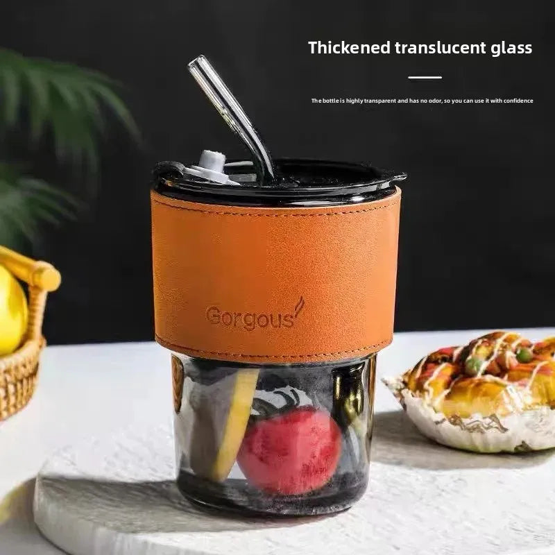 Bamboo node glass straw cup with thickened translucent glass and a brown leather sleeve on a white table