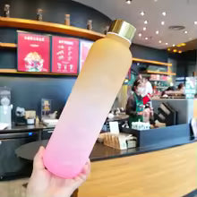 Clarify.pk gradient color outdoor water cup with gold lid held in hand inside a cafe