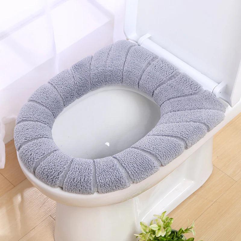 Gray washable toilet seat cover made of soft fabric fitted on a white toilet seat