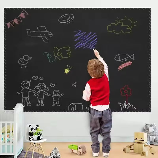 Child drawing on large blackboard sticker for wall with colorful chalk drawings in a playroom