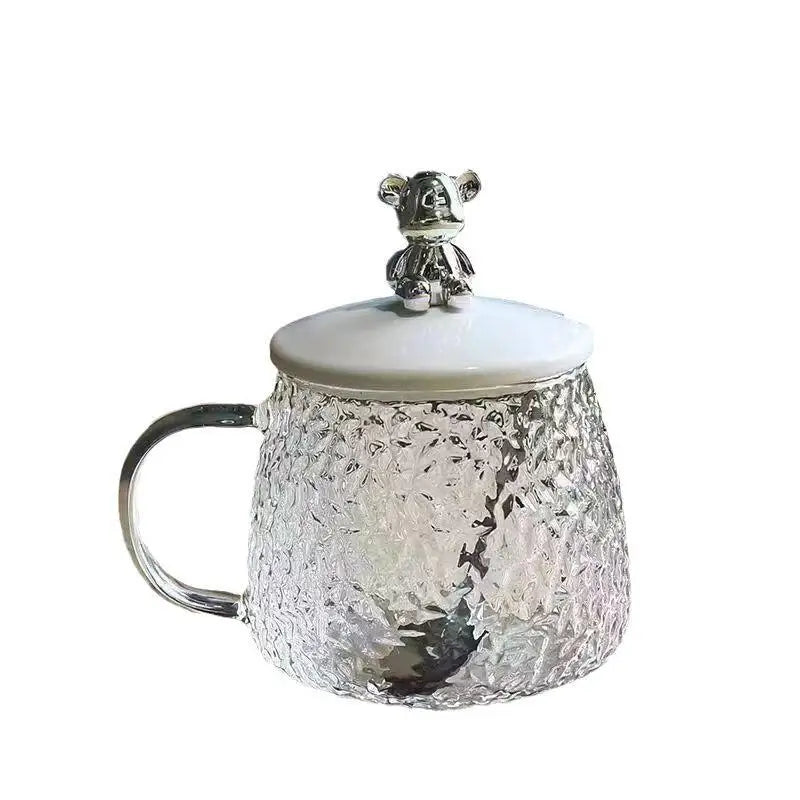 Hammered glass coffee cup with lid featuring a textured design and a decorative bear-shaped handle