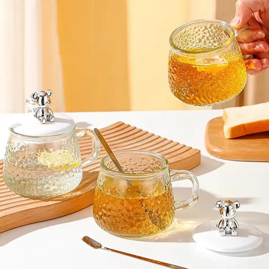 Hammered glass coffee cup with lid and bear-shaped knob from Clarify.pk holding tea on white table