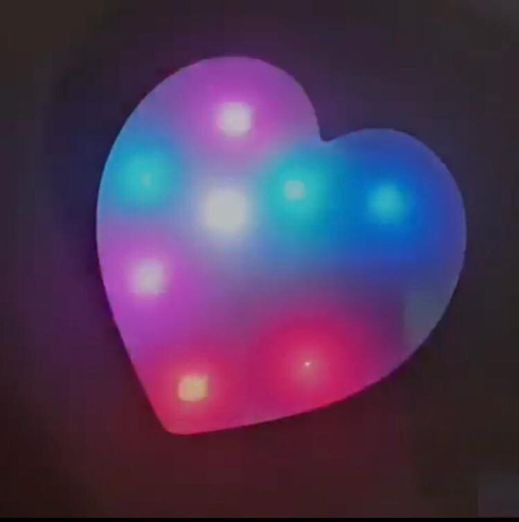 Colorful heart shaped LED lamp glowing with pink, blue, and purple lights on a dark background