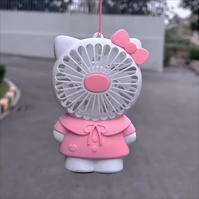 Hello Kitty handheld fan in pink and white with bow and dress design hanging outdoors