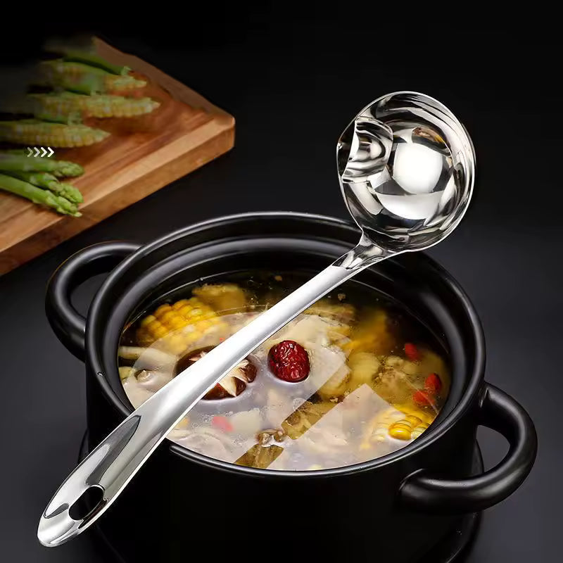 Stainless steel oil separator spoon resting on black pot with soup and vegetables by Clarify.pk