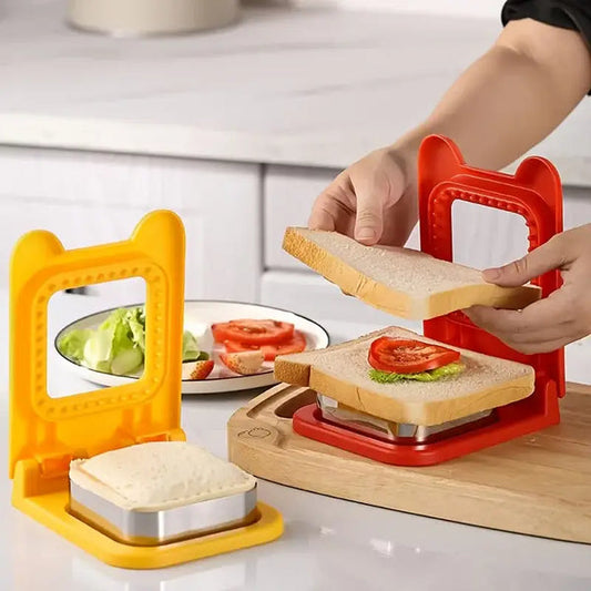Red and yellow sandwich cutter and sealer set in kitchen with hands pressing sandwich filled with lettuce and tomato