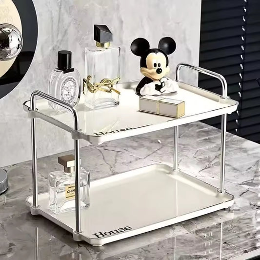 White 2 tier desktop cup rack organizer with metal handles holding perfume bottles and a Mickey Mouse figurine