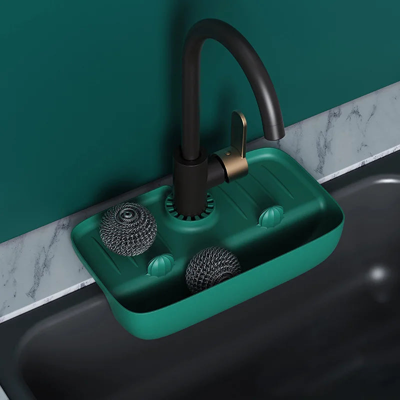 Clarify.pk green silicone faucet mat holding kitchen scrubbers under black faucet on marble countertop