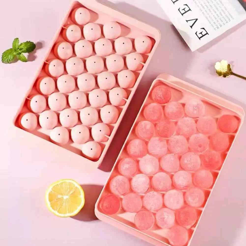 Two pink round ice cube trays filled with perfectly shaped round ice cubes for drinks