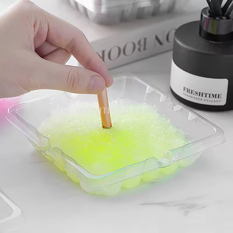 Clear plastic disposable ashtray 4 pieces set with yellow gel beads holding a cigarette on a white surface