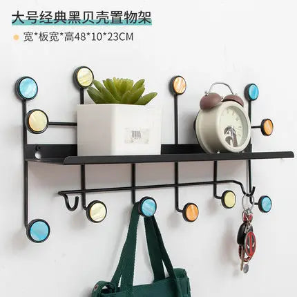 Iron art key holder for home with colorful round hooks and a black shelf holding a plant and clock