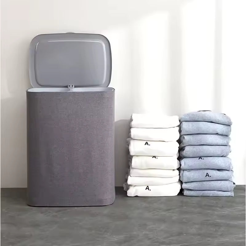 Gray Japanese style clothes hamper with a lid next to neatly folded white and gray towels on a gray floor