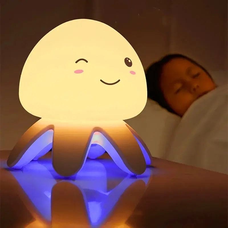 Cute jellyfish night light glowing with soft yellow and blue light beside sleeping child