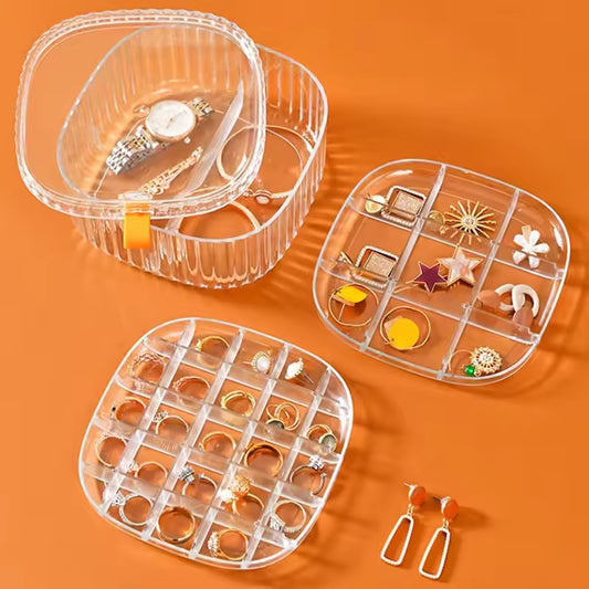 Clear 3 layer jewelry storage case by Clarify.pk with compartments holding rings, earrings, and watches