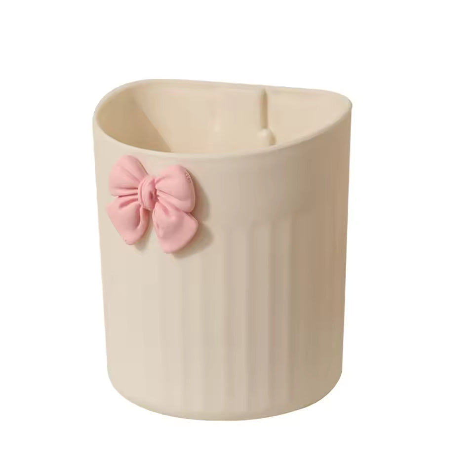 Beige kawaii pen holder for desk with vertical grooves and a pink bow decoration