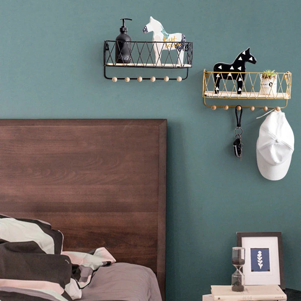 Modern key holder wall rack with hooks in black and gold mounted on green wall above bed
