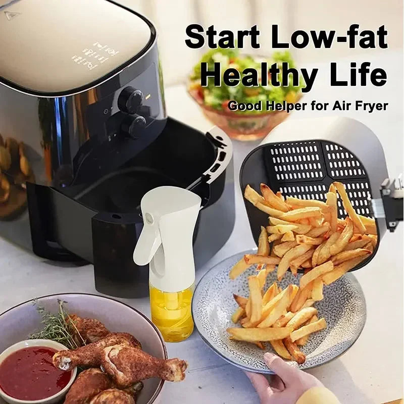 kitchen oil spray bottle with yellow oil next to air fryer and plate of fries for healthy cooking