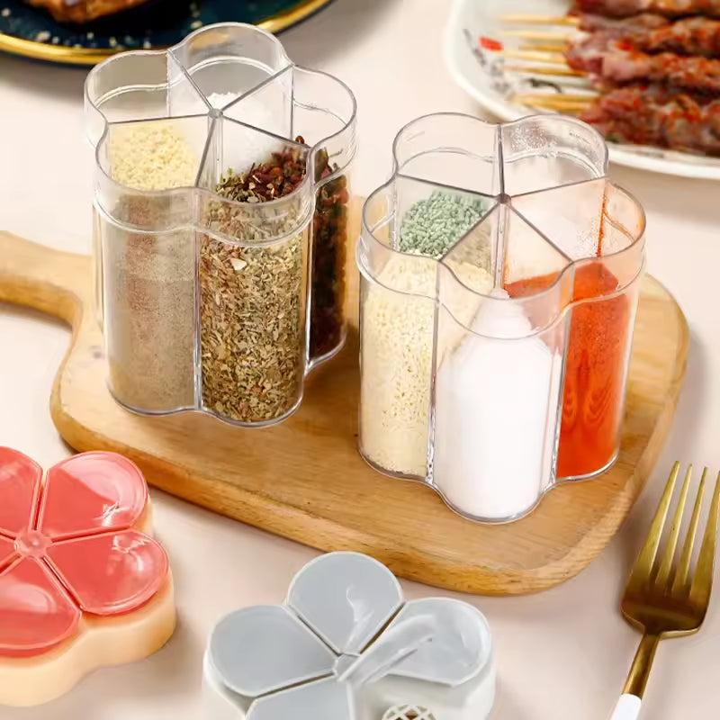 Clear kitchen seasoning container with lids holding various spices on wooden board
