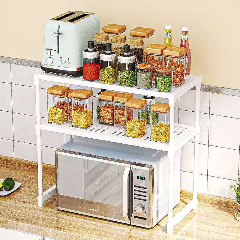 White kitchen storage rack organizer holding jars, condiments, toaster, and microwave on kitchen countertop