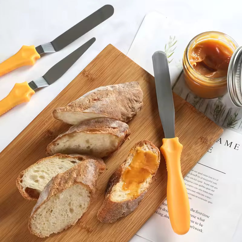 Clarify.pk cake spatula 3 piece set with yellow handles displayed alongside sliced bread and jam on wooden board