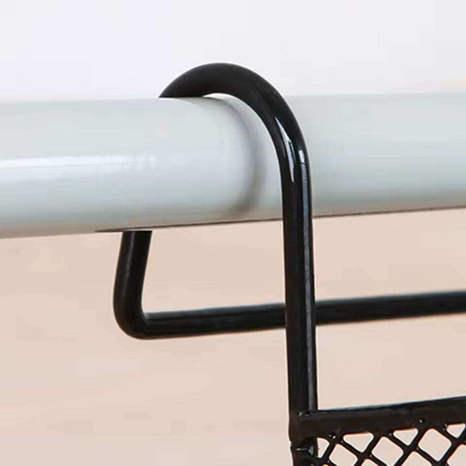 Close-up of black large capacity metal basket for bed hanging on white bed frame rod