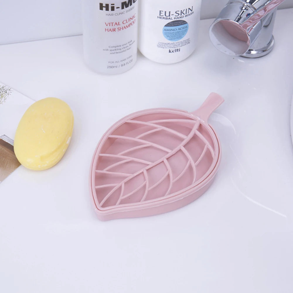 Clarify.pk pink leaf shape soap dish on white sink countertop next to yellow soap and shampoo bottles