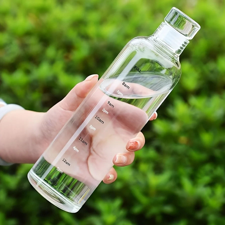 Clear leakproof sport water bottle with time markers held in hand against green background