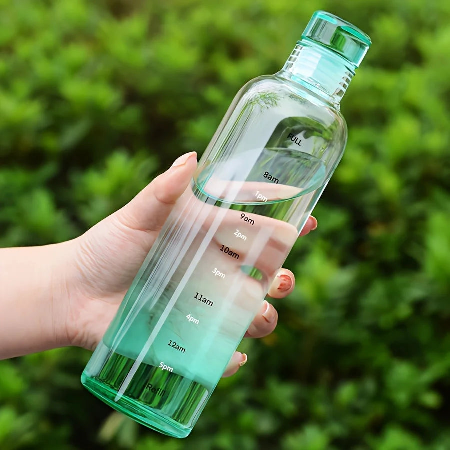 Clear green leakproof sport water bottle with time markings held in hand outdoors