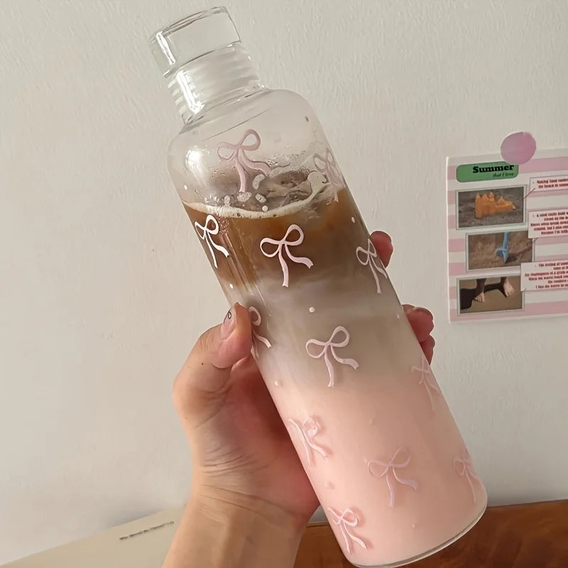 Clarify.pk leakproof sport water bottle with pink bow design held in hand filled with layered iced coffee and milk