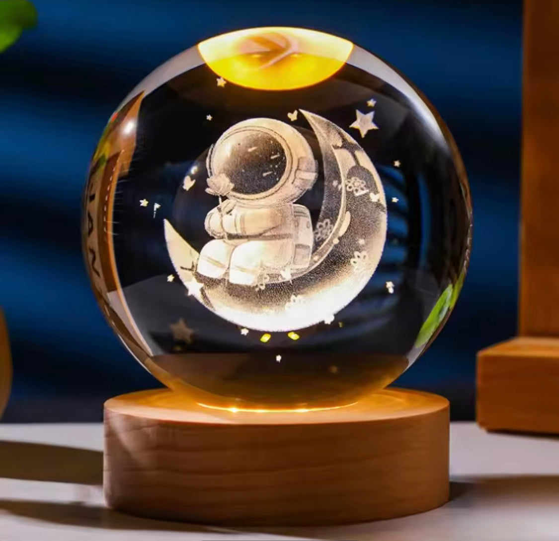LED astronomy night light featuring a glowing astronaut sitting on a crescent moon inside a glass sphere