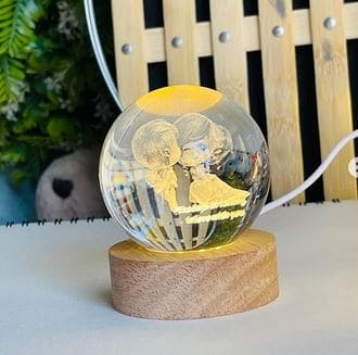 LED astronomy night light featuring a 3D etched couple inside a clear crystal ball on a wooden base