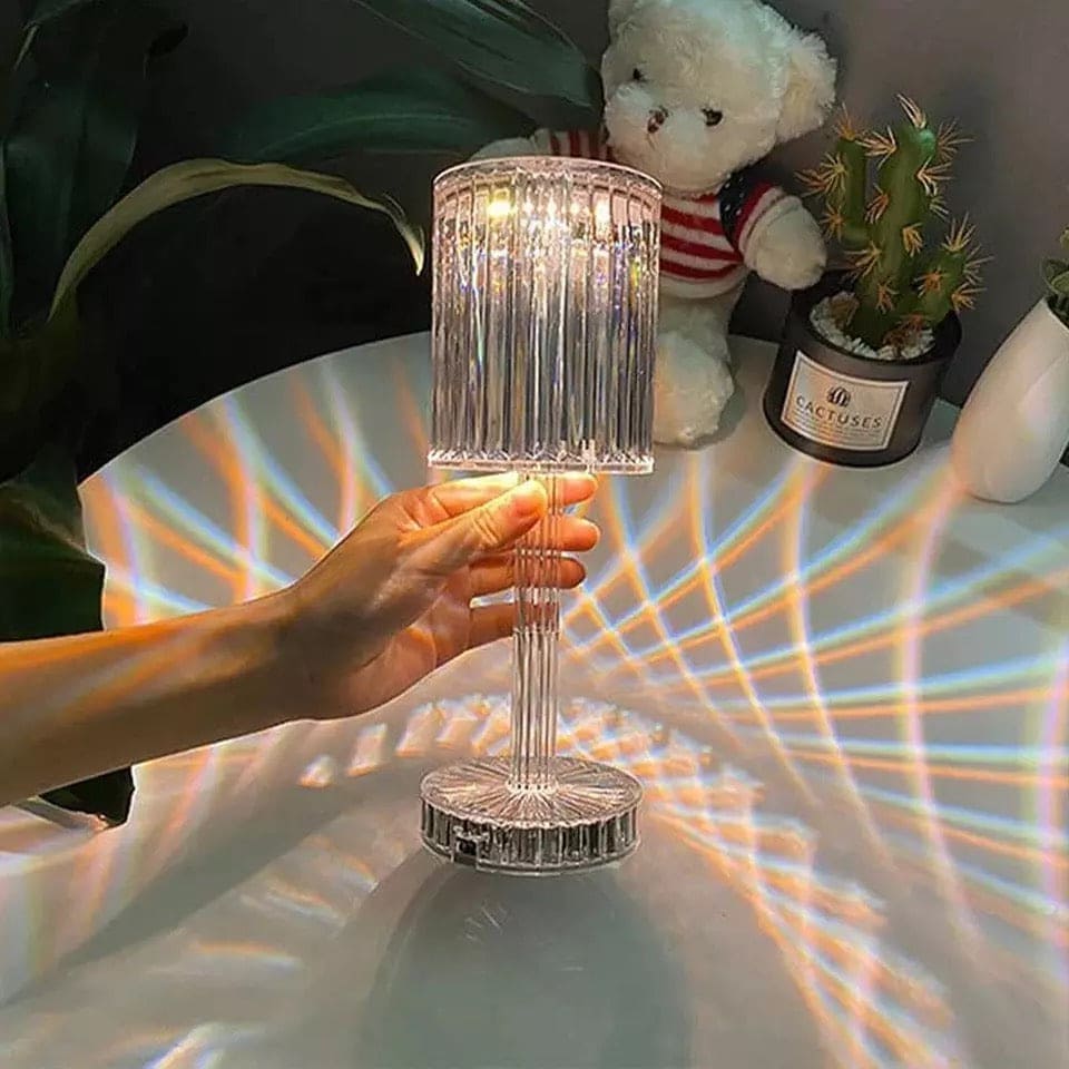 Hand holding led crystal projection lamp casting colorful light patterns on white surface