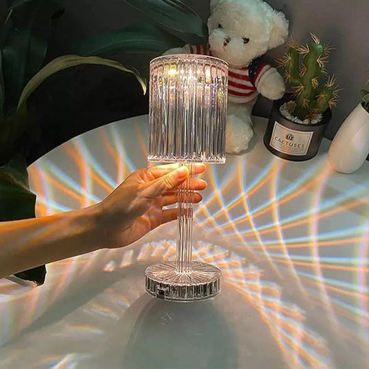 Hand holding led crystal projection lamp casting colorful light patterns on white surface