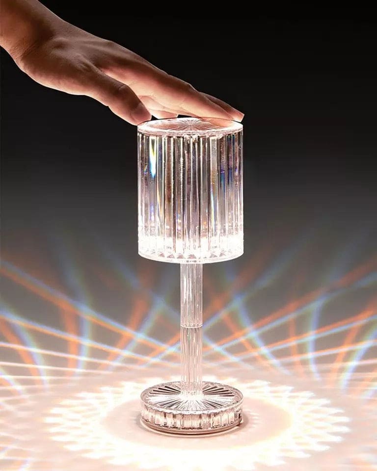 Hand touching a stylish led crystal projection lamp casting colorful light patterns on surface