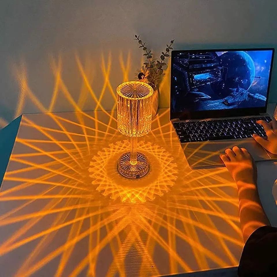 Clarify.pk led crystal projection lamp casting intricate warm light patterns on desk next to a laptop
