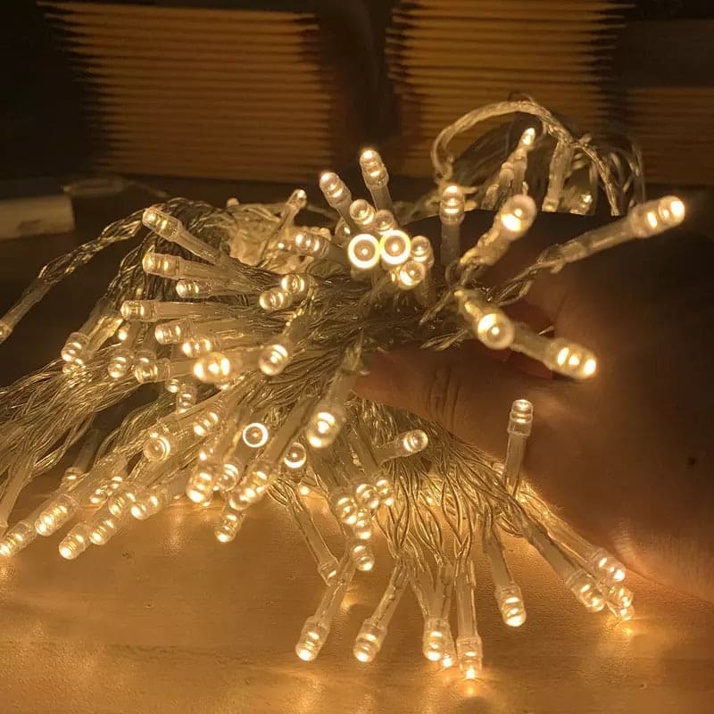Warm white LED curtain lights for home decor glowing in a hand with transparent wiring