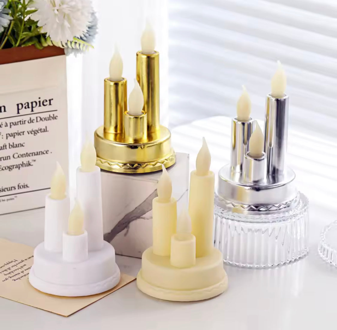 Set of LED flameless candle for home decor in gold, silver, white, and cream colors on white surface