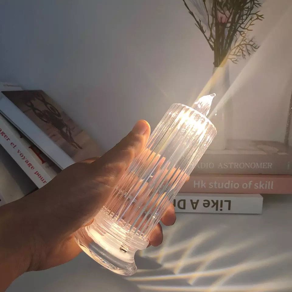 Hand holding a glowing LED flameless candle lamp with a textured glass design creating warm light patterns