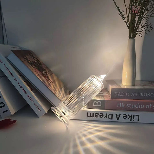 Clarify.pk LED flameless candle lamp with clear ribbed glass design casting warm light on books and table