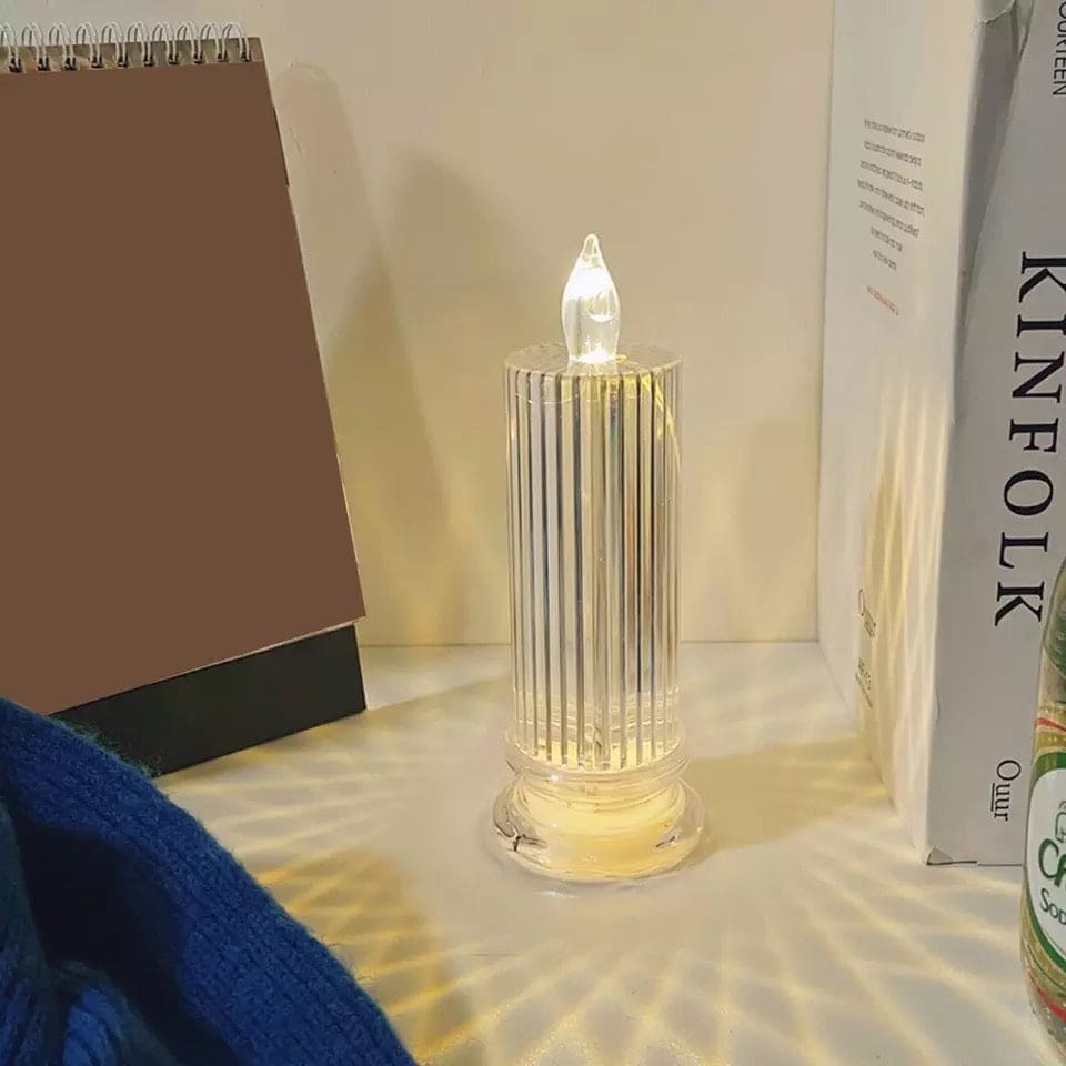 LED flameless candle lamp with clear ribbed glass design emitting soft warm light on a table