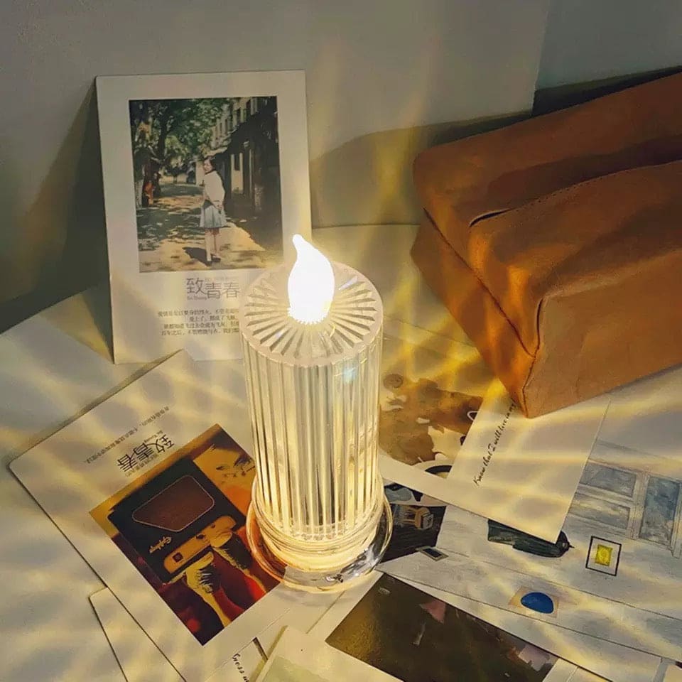 Clarify.pk LED flameless candle lamp on table with warm glowing light and decorative photos nearby